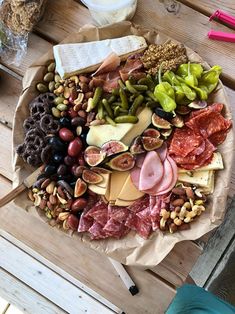 an assortment of meats and cheeses on a wooden table