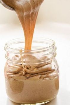 a jar filled with peanut butter being poured into it