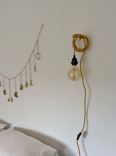 a lamp that is on the side of a wall next to a bed with white sheets