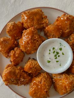 a white plate topped with chicken wings and ranch dip