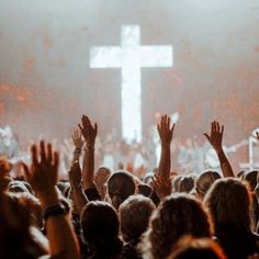 a group of people with their hands up in front of a cross on a stage