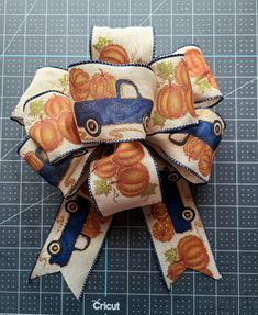 a close up of a bow with pumpkins on it and blue ribbon around the bow