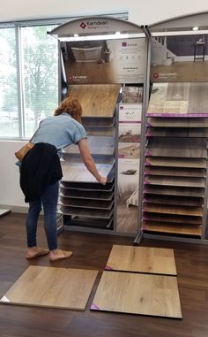 a woman standing in front of a display case filled with wooden flooring