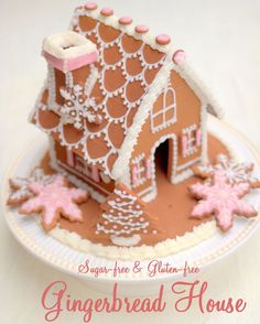 a gingerbread house is on a plate with icing and pink snowflakes