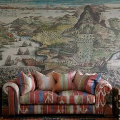 a couch sitting in front of a wall with a large painting on it's side