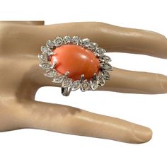 an orange stone ring sitting on top of a mannequin's hand in front of a white background