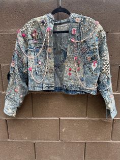 ˚˖𓍢ִ໋˖o.:: RARE FIND ::.o⋆ 🏷️ Vintage 1980s Tony Alamo Jeweled Denim (Levi's) Jacket. Available for sale is a cropped denim jacket dripping in jewels by Tony Alamo. Acid washed denim base constructed into an open, cropped silhouette with padded dolman-style sleeves. Embellished in beads, studs, stones, charms, and chains, this weighty jacket sparkles from every angle.  These jackets were once the height of fashion, worn by icons like Mr. T, Sonny Bono, Michael Jackson, Burt Reynolds, and Dolly Parton.   Step into a piece of fashion history where timeless style meets unparalleled craftsmanship. This jacket is a bold statement, meticulously designed with intricate detailing that captures the essence of retro glamour and modern sophistication. Whether you're looking to stand out in a crowd 80s Denim Outfit, Denim Jacket 80s, Sonny Bono, Repurposed Crafts, Denim Jacket Cropped, Jeweled Collar, 80s Denim, Levis Denim Jacket, Burt Reynolds