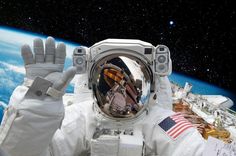 an astronaut in outer space waving at the camera with his hands up and earth in the background