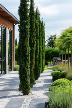 an outdoor garden with stone walkways, trees and graveled path leading to patio area