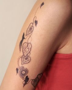 a woman's arm with flowers and hearts tattooed on the back of her shoulder