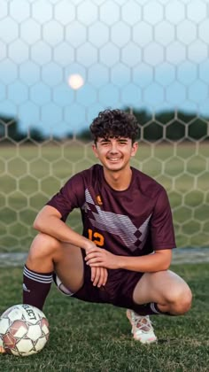 a young man sitting on the ground next to a soccer ball