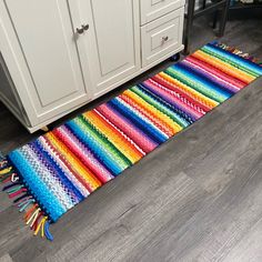 a multicolored rug on the floor next to a white cabinet and countertop