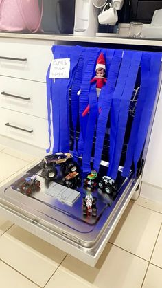 the elf in the kitchen has been made out of blue paper and is sitting on top of an oven