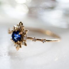 a close up of a ring with a blue stone in the middle and diamonds around it