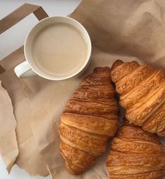 three croissants sitting next to a cup of coffee