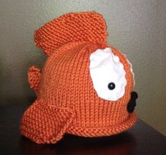 an orange knitted hat with a black nose and white eye patch on the front