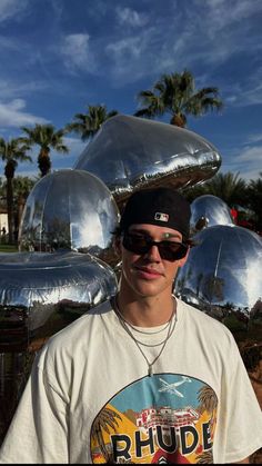 a young man standing in front of some shiny metal objects on display at a park