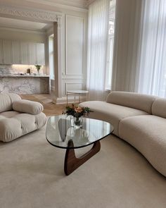 a living room filled with furniture and a glass table in front of a large window