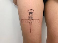 a woman's thigh with a small tattoo of a plane on it and the bottom part of her leg