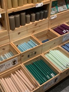 many different colored candles are on display in the store's wooden shelves and bins