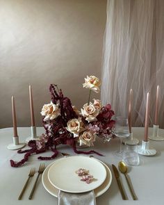 the table is set with flowers, candles and silverware for an elegant dinner party