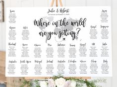 a seating chart with white flowers and greenery on the table for a wedding ceremony