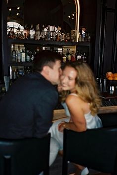 a man and woman sitting at a bar kissing