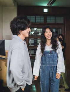 two people standing next to each other in front of a computer screen and smiling at each other