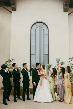 a group of people standing next to each other in front of a building holding flowers