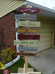 a wooden sign with many different signs attached to it's sides in front of a house