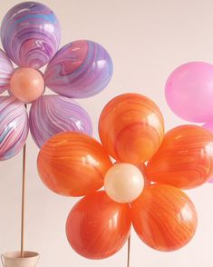 there are three balloons in the shape of flowers and one is pink, orange, and purple