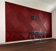 a room with a table and some chairs in front of a red wall that has geometric designs on it