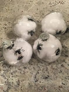 four glass balls decorated with black and white spider webs are sitting on a marble countertop