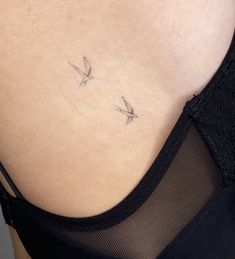 the back of a woman's stomach with two small birds on her left side