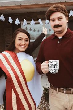 a man and woman dressed in costumes holding coffee mugs while standing next to each other