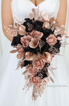 a bridal bouquet with black, pink and gold flowers in the bride's hand