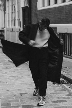 black and white photograph of woman walking down the street with her coat over her shoulders