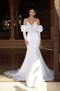 a woman in a white wedding dress standing outside