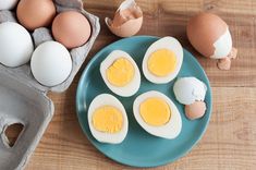 four eggs on a blue plate next to an egg shell