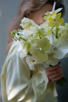 a woman holding a bouquet of white and yellow flowers