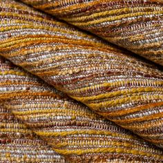 a close up shot of the texture of a handwovened wool fabric in brown, yellow and beige tones