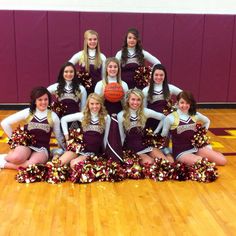 a group of cheerleaders posing for a photo in front of a basketball ball