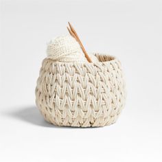 a white woven basket with a wooden stick sticking out of it's top and bottom