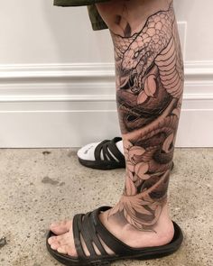 a man's leg with a dragon tattoo on it, and his foot in sandals