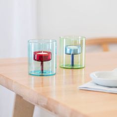 two glass candles sitting on top of a wooden table