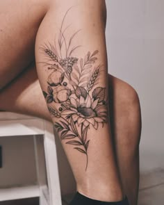 a woman's leg with flowers and leaves on it