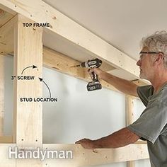 a man is working on the framing of a wall with a drill and screwdriver