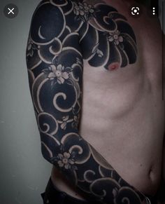 a man's arm and shoulder covered in black ink with white flowers on it