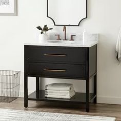 a bathroom vanity with two drawers and a mirror on the wall above it, next to a basket full of towels