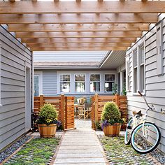 a bike is parked in front of a house with a pergolated walkway between two buildings